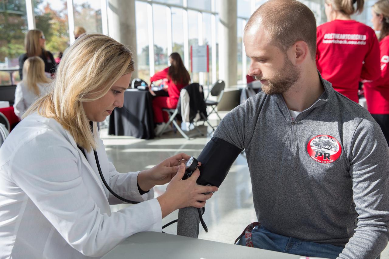 A participant is having his pulse taken by a nurse practitioner 