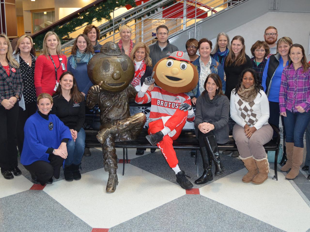 Buckeye Wellness Innovators pose with Brutus Buckeye next to the Brutus Buckeye bench statue in the Ohio Union.